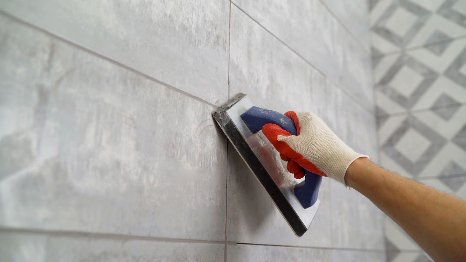 A person is using a sponge to grout a tile wall.