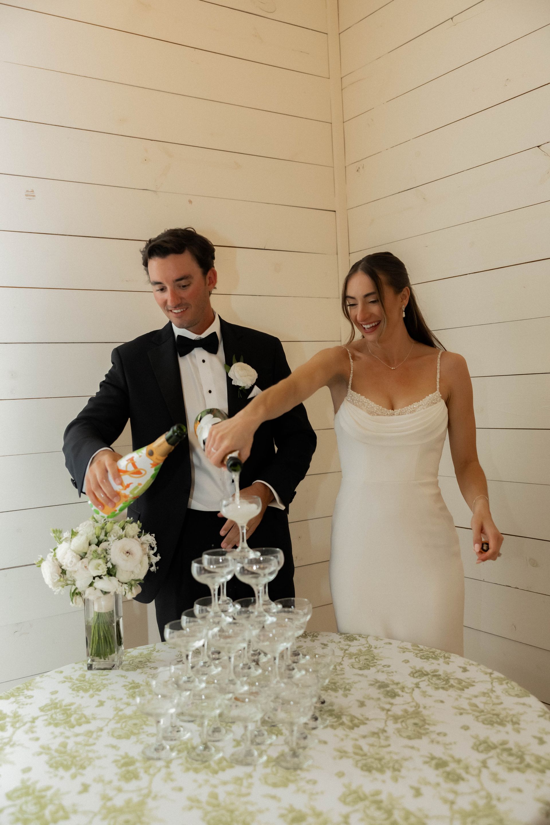 Bride and groom pouring champagne into a glass tower at a wedding reception