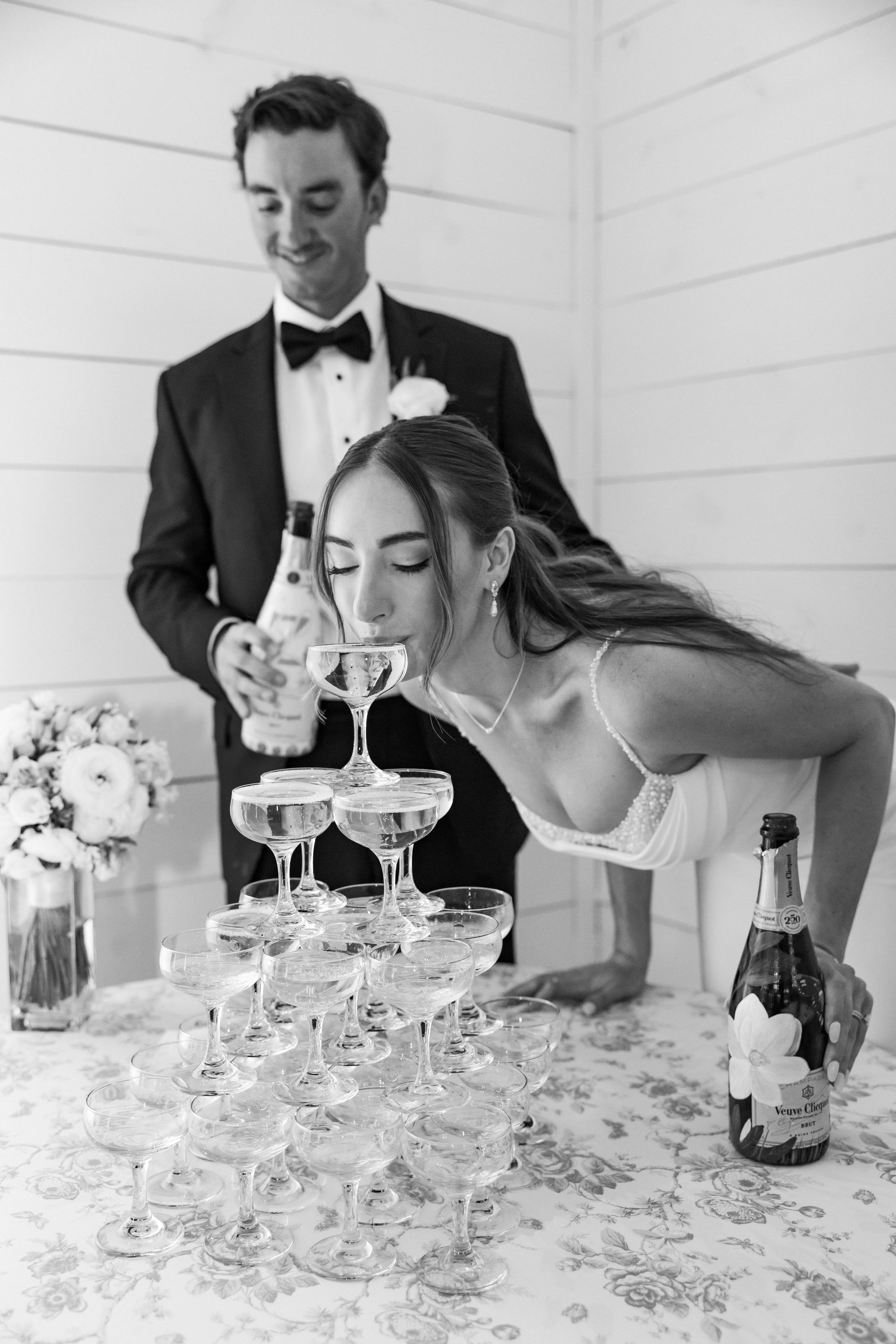 Bride and groom stacking champagne glasses at a wedding reception table