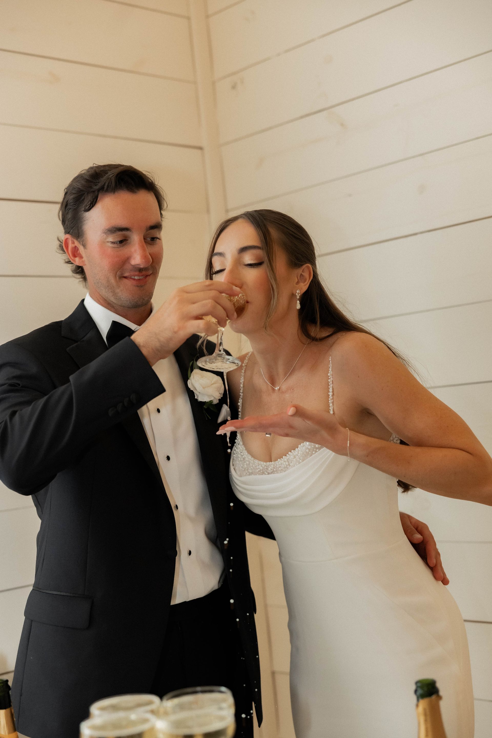 Bride and groom in formalwear sharing a toast at a wedding reception