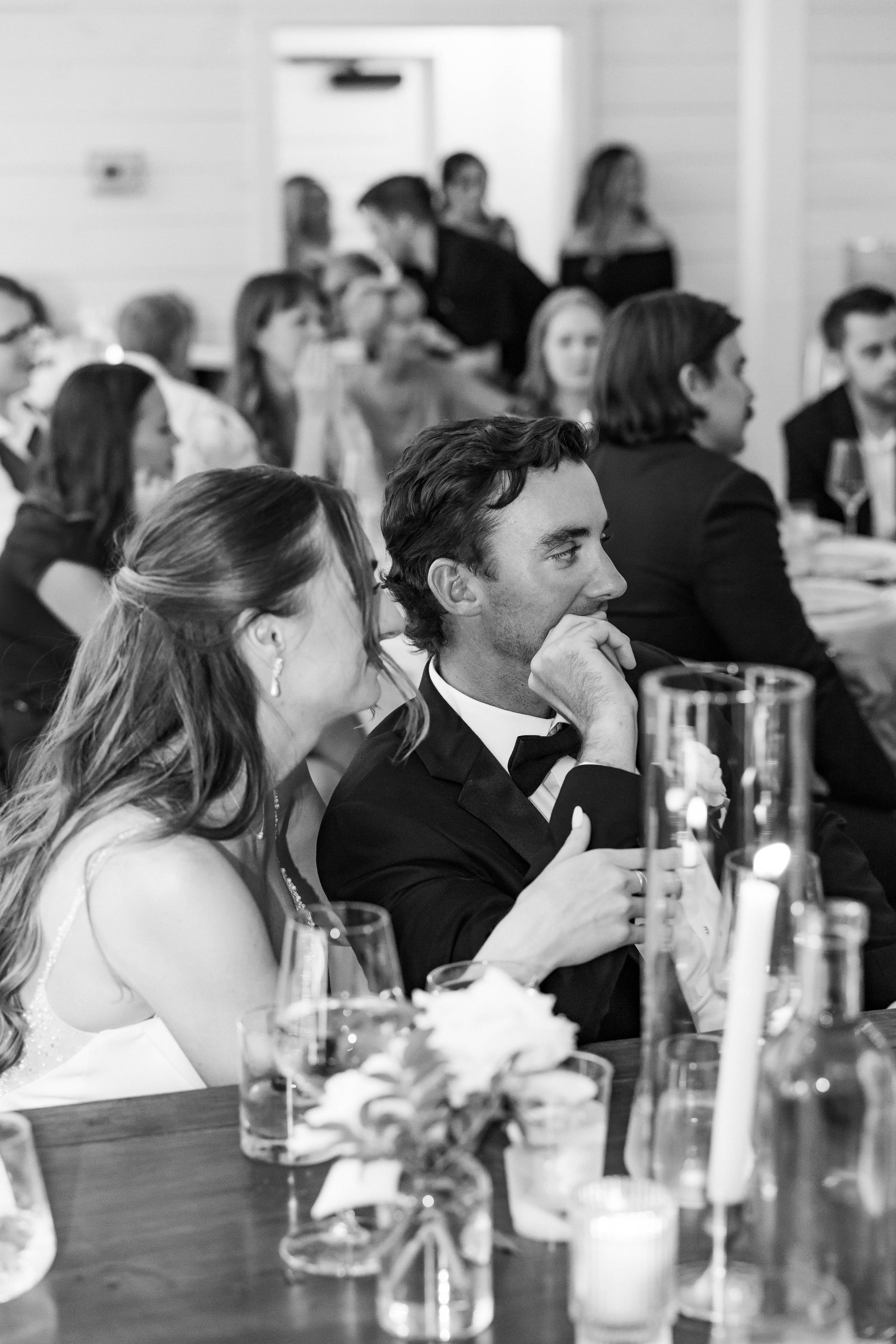 Guests seated at a banquet table, listening attentively at an indoor event