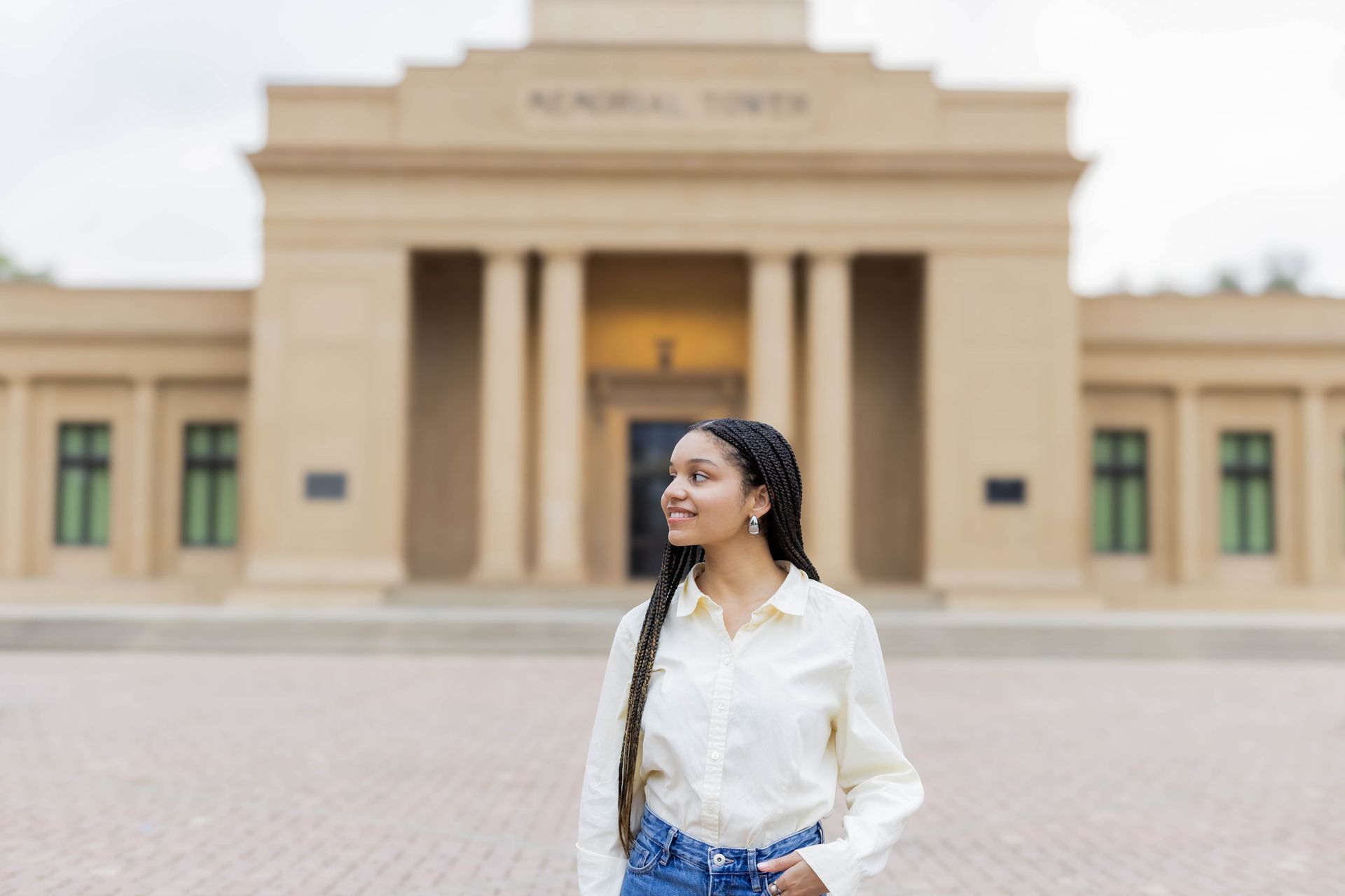 Woman in white blouse standing in front of a beige museum building with columns