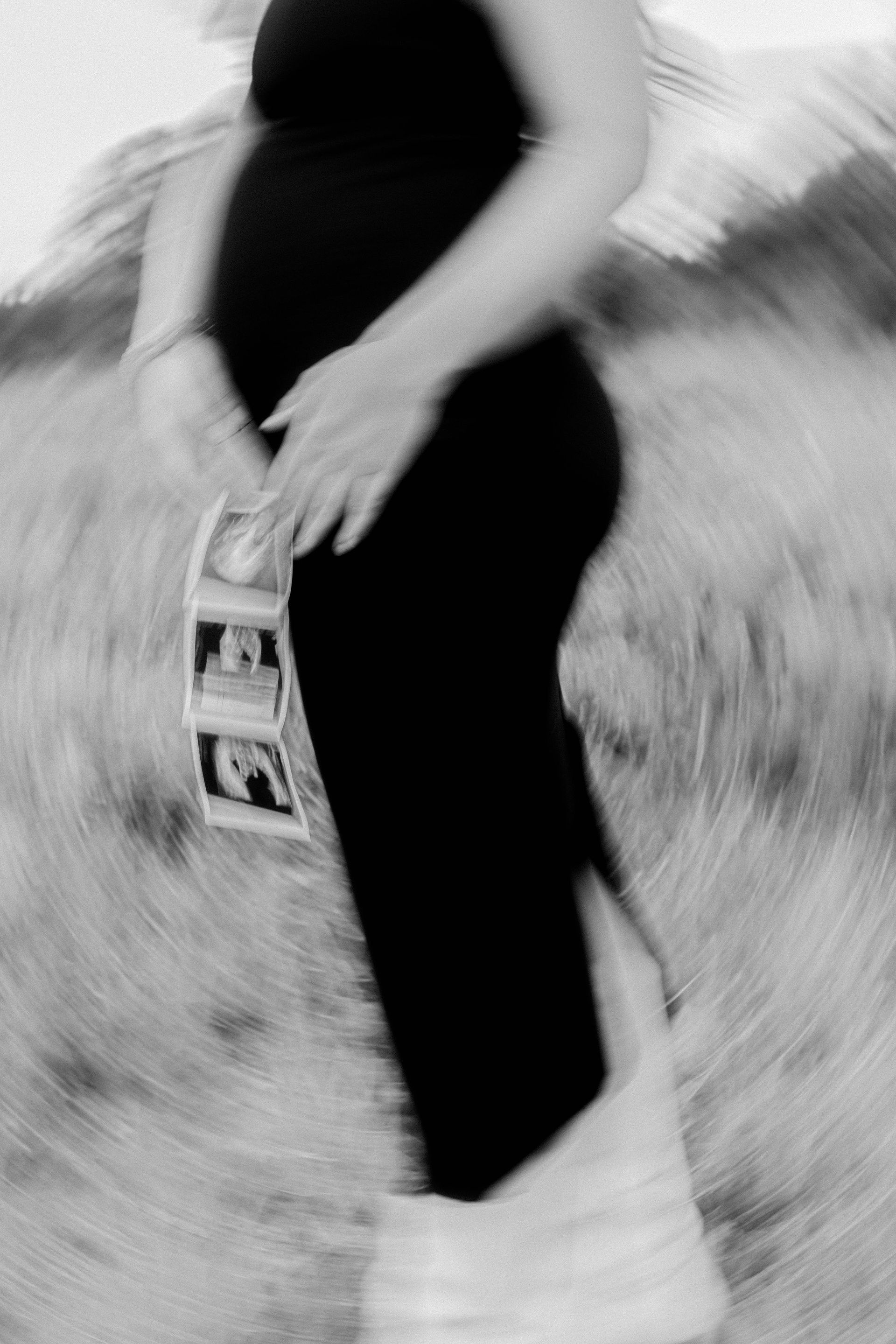 Person in a black dress and white boots standing in a grassy field, holding a small book or card.