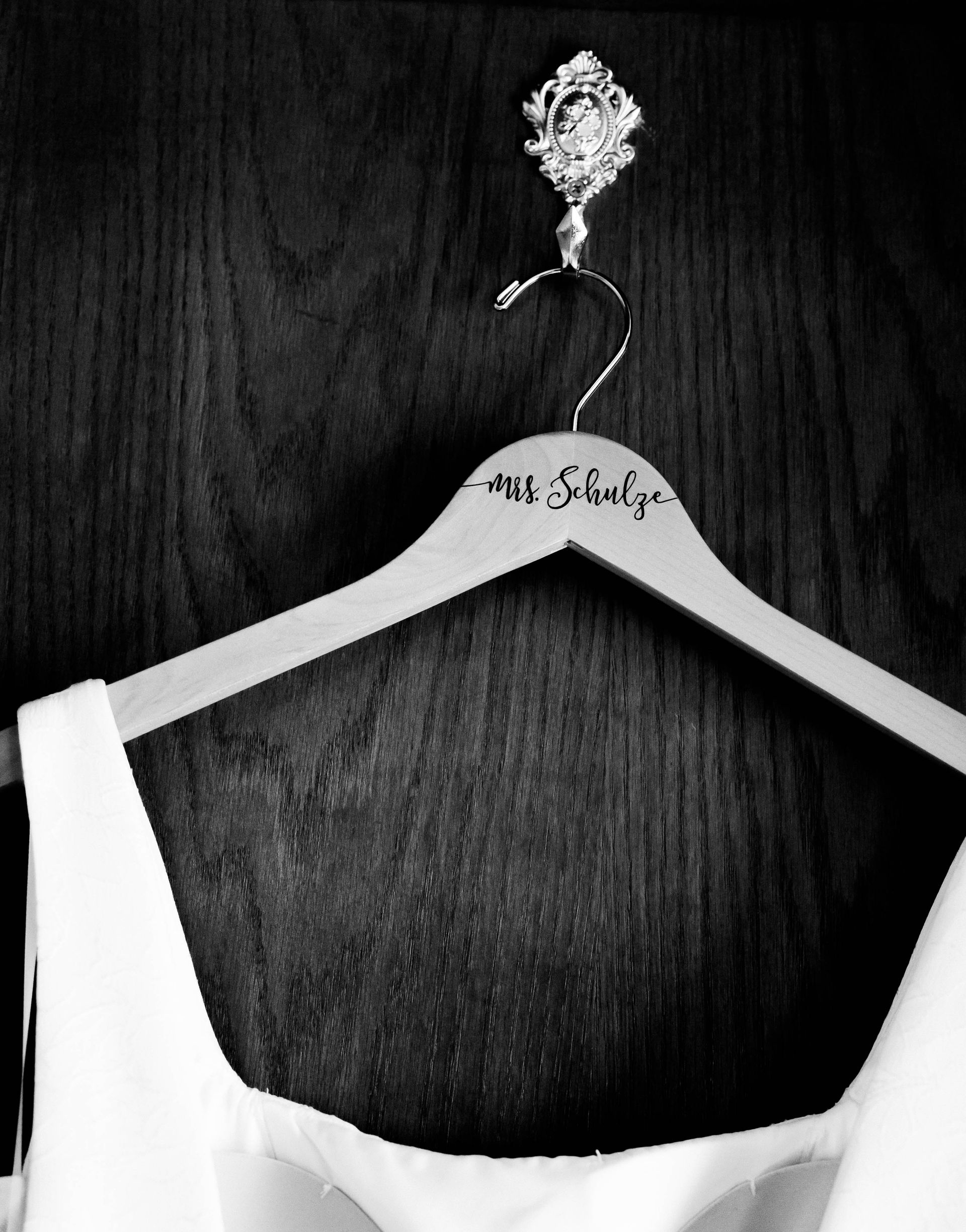 White garment on a hanger against a dark wooden background.