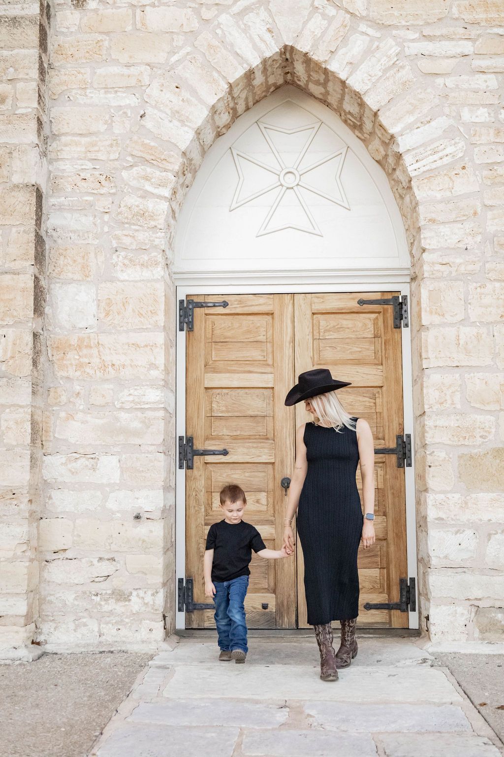 Woman and child walking toward a wooden church door under a stone archway