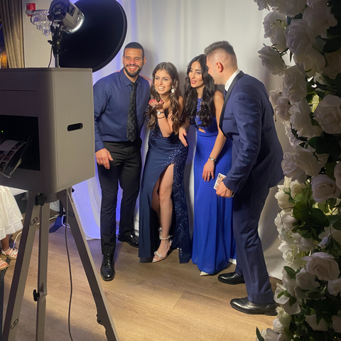 Four people posing in formal blue outfits at an indoor event photo booth