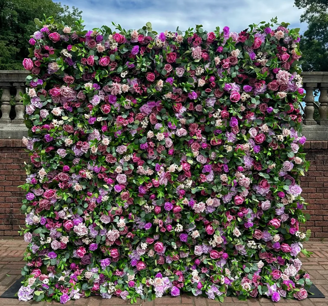Flower-covered garden wall with pink, purple, and white blossoms against a stone fence
