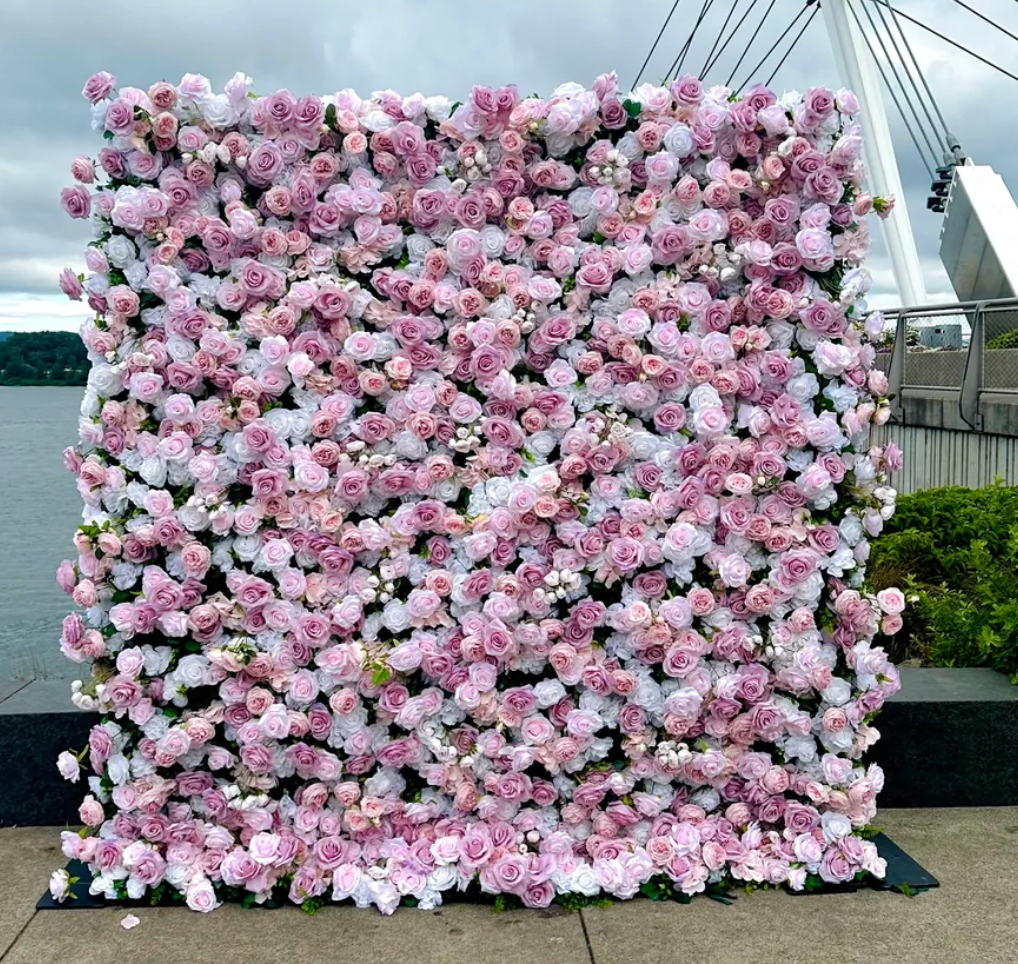 Large square floral wall of pink and white flowers outdoors on a paved walkway