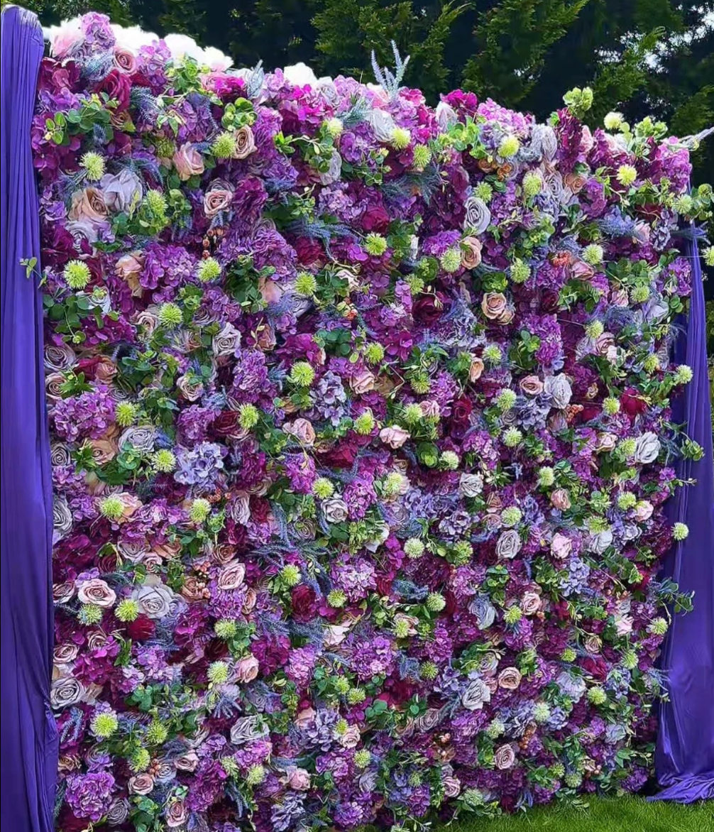 Purple, pink, and white flower wall backdrop with dense blossoms and greenery