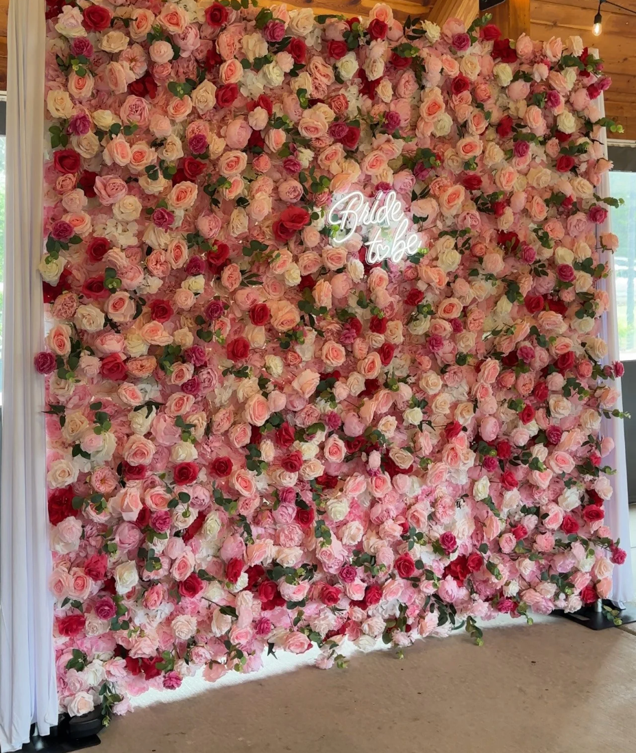 Pink and white floral wall backdrop with a glowing neon sign centered on it