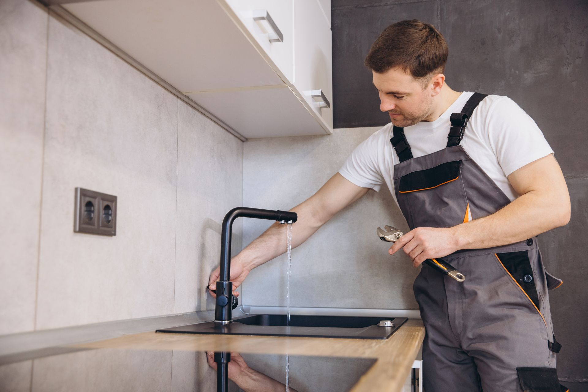 A professional plumber testing a faucet after completing a home water softener replacement service A professional plumber testing a faucet after completing a home water softener replacement service