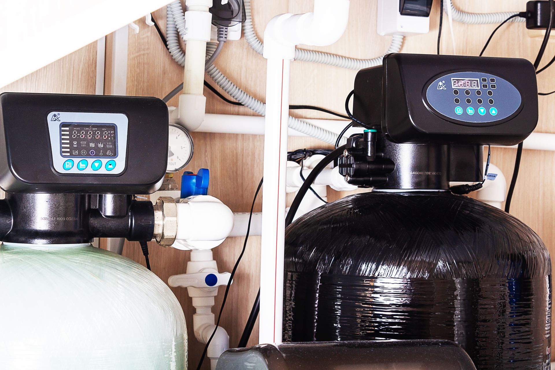 Water filtration tanks with digital control valves and connected plumbing system. Water filtration tanks with digital control valves and connected plumbing system.