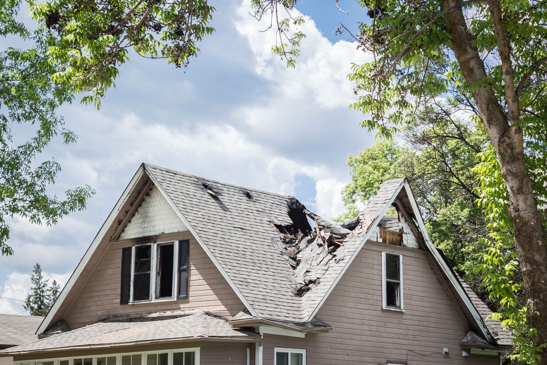 A house with a roof that has been damaged by a fire.