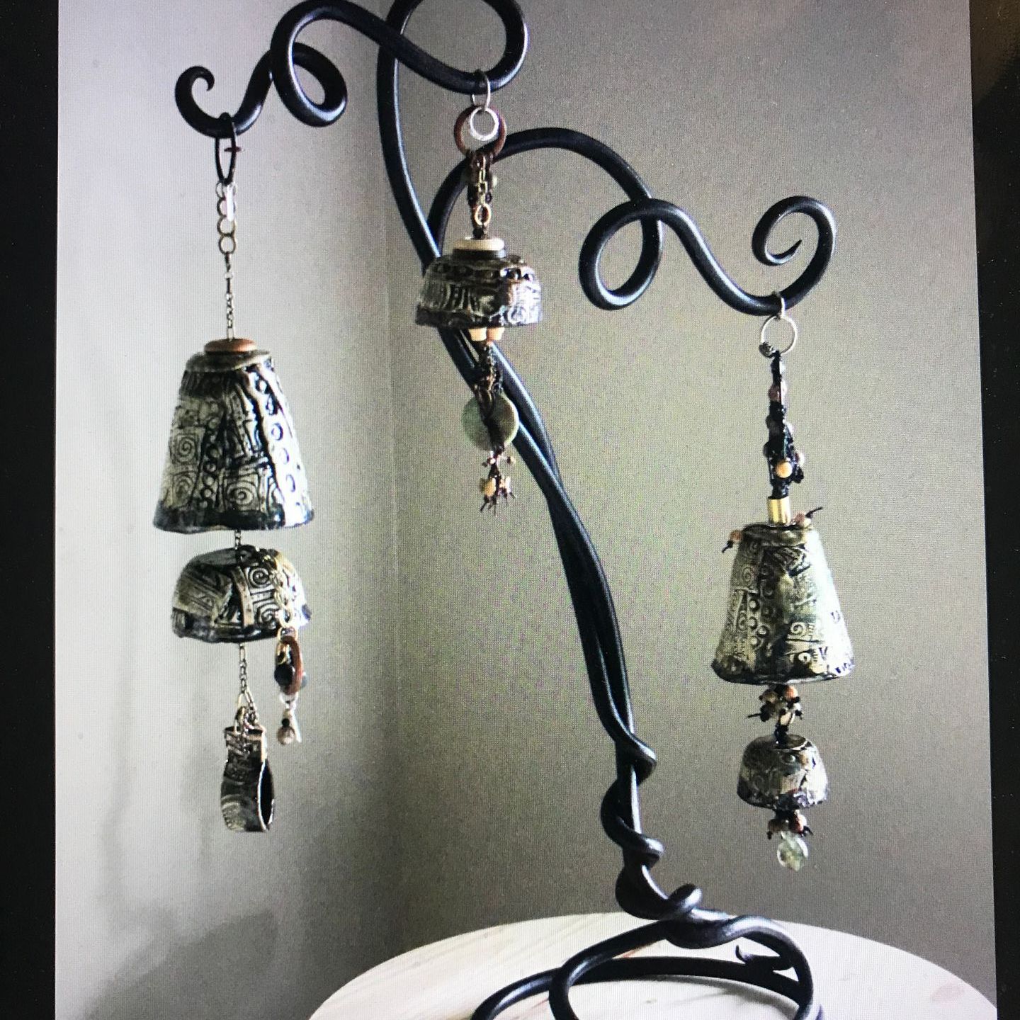 Three bells are hanging from a wrought iron stand