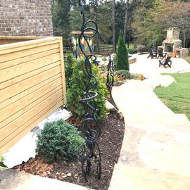 A walkway leading to a backyard with a fence and a fireplace.