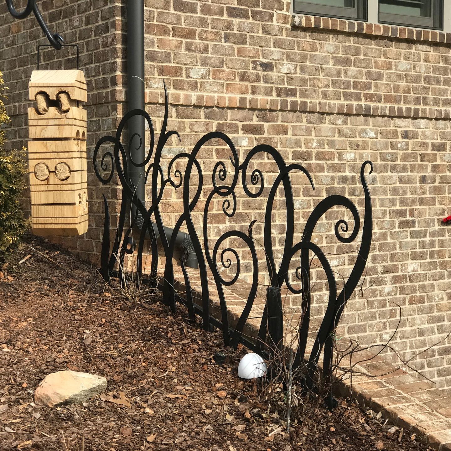 A wrought iron fence is sitting on the side of a brick building.
