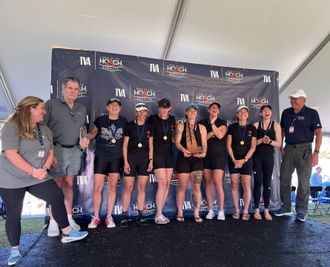 A group of people are posing for a picture in front of a wall that says ' ii ' on it