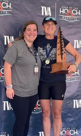 Two women are posing for a picture with a trophy.