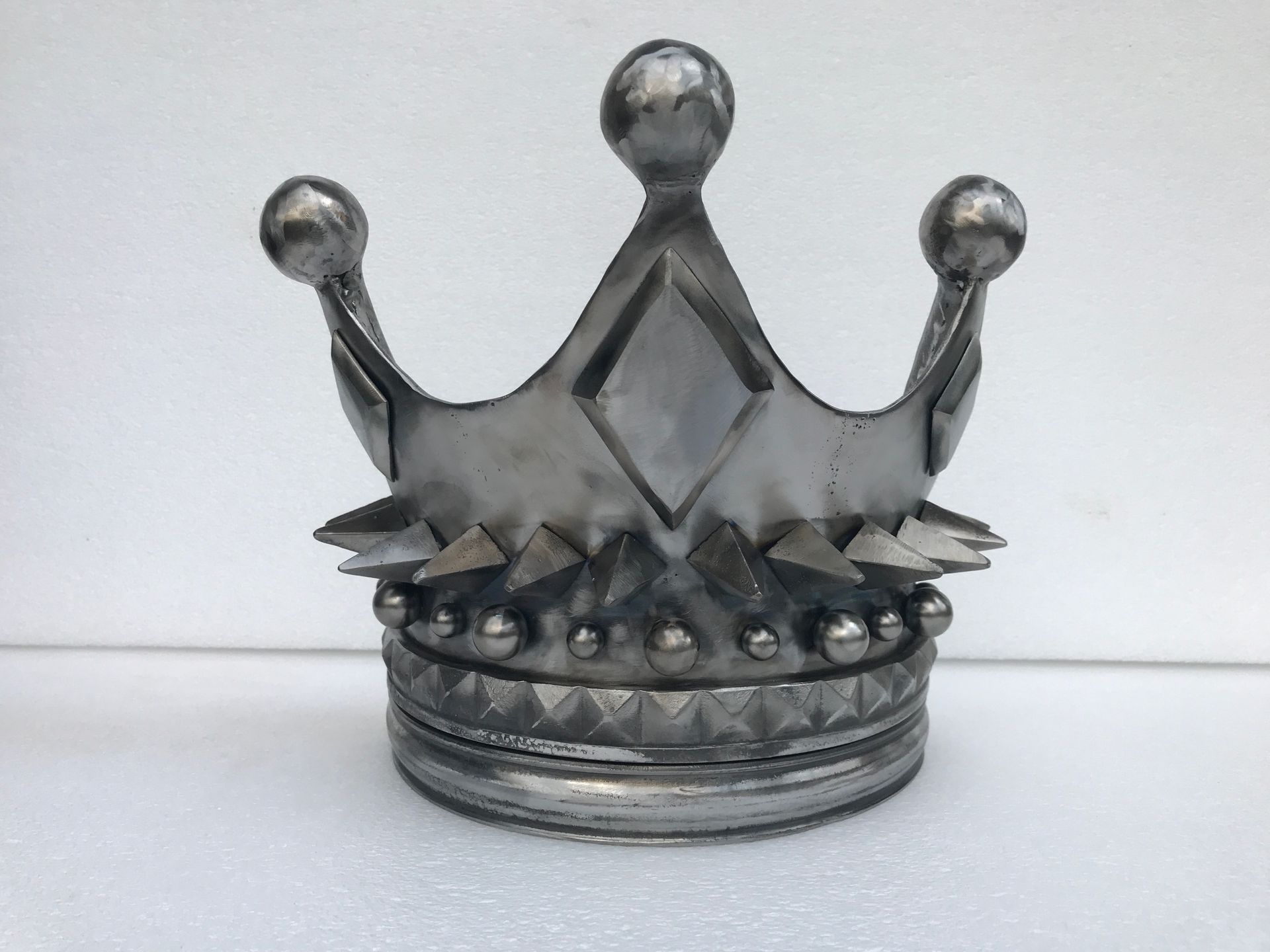 A metal door pull crown with spikes on top of it