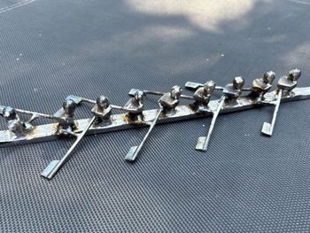 A group of people are rowing a boat on a black surface.