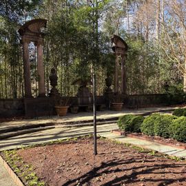 A garden with a labyrinth in the middle of it and trees in the background.