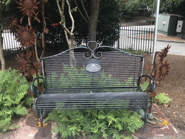 A wrought iron bench is sitting in the middle of a garden.