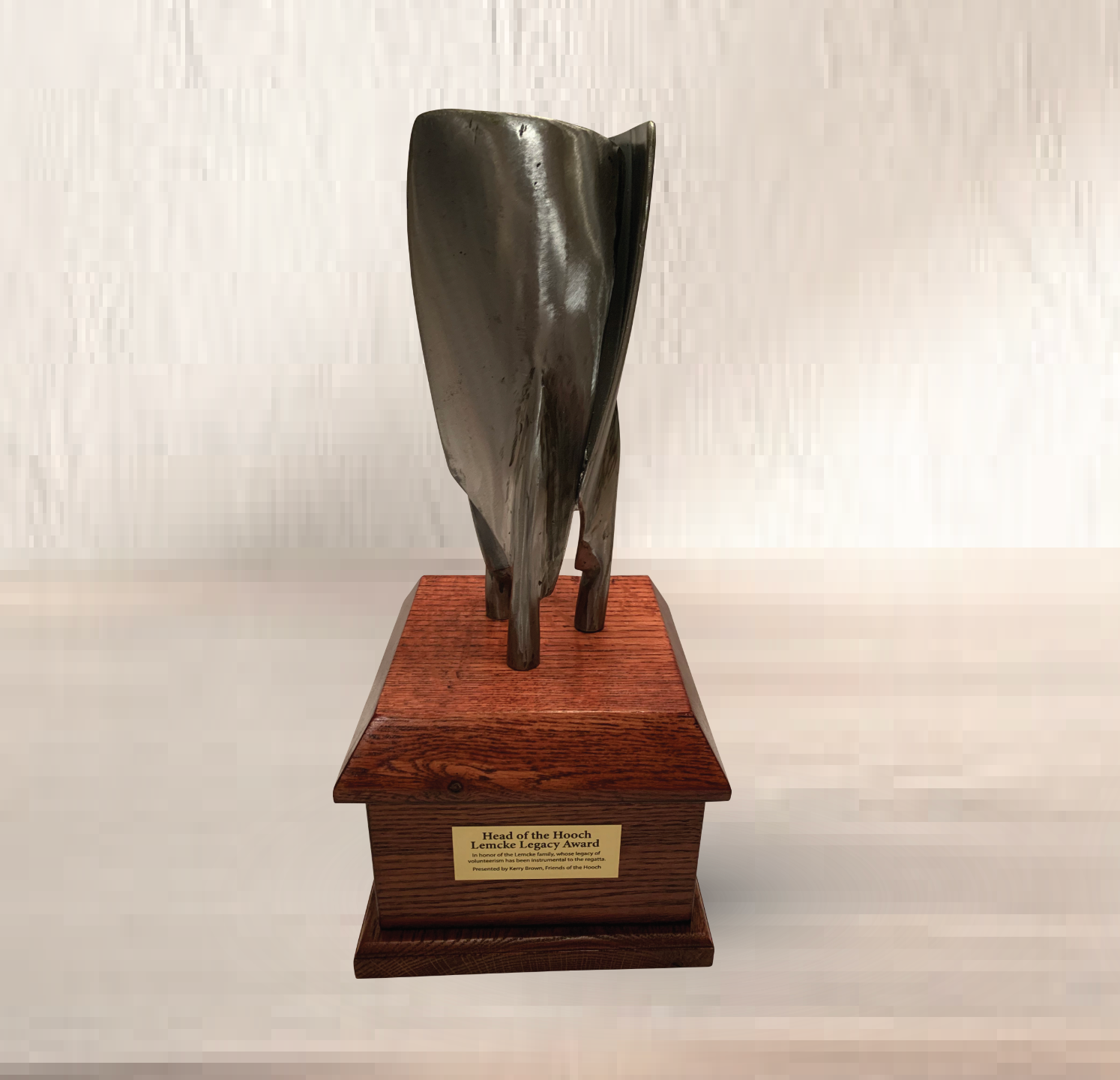 Abstract black sculpture on a wooden base with a small plaque, against a light background