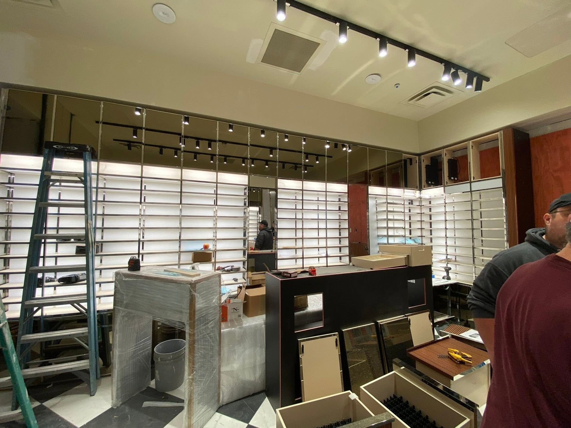 Modern office interior with shelving, desks, and people working under bright ceiling lights