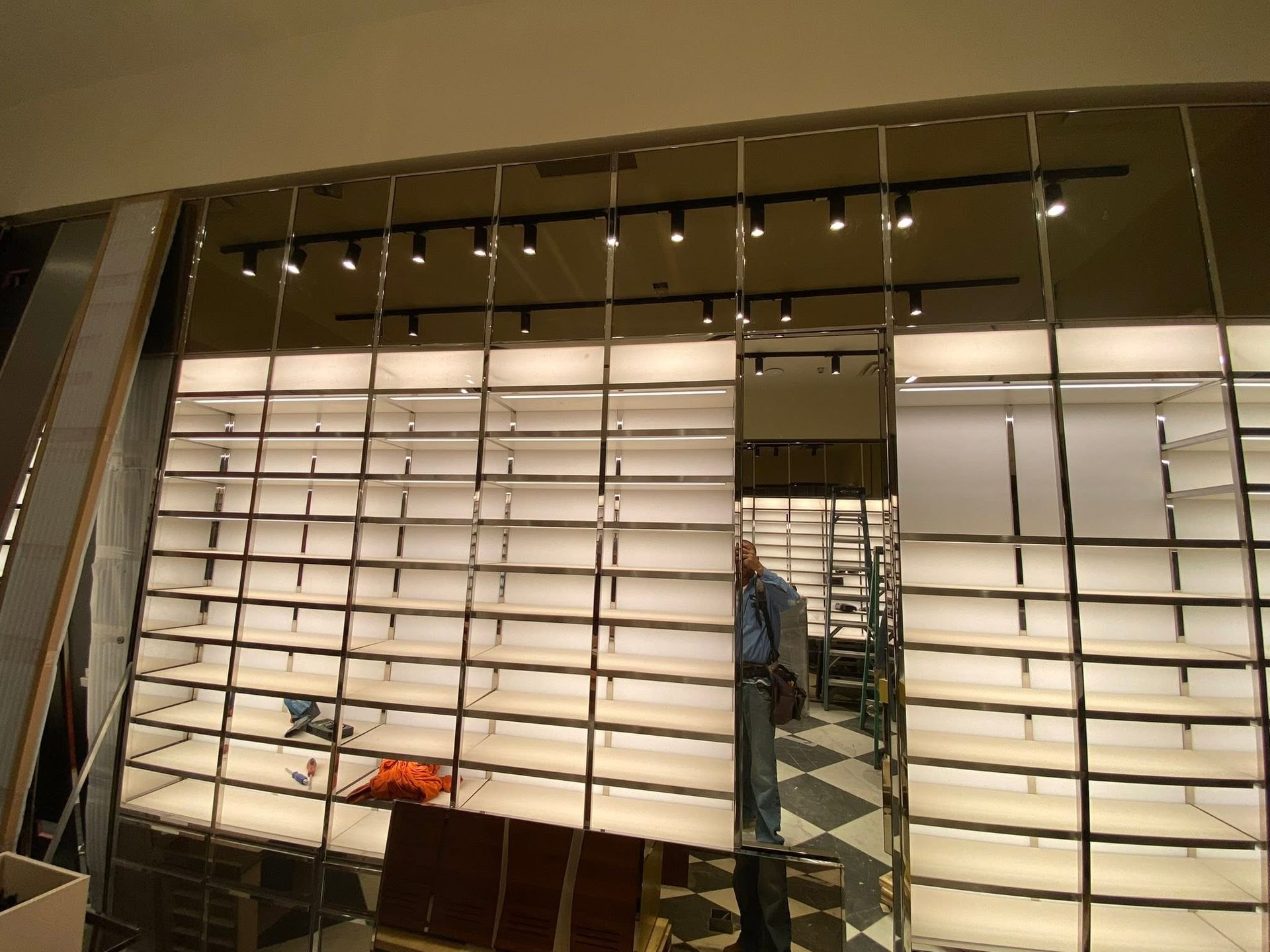 Modern storefront with white slatted panels, a central mirror-like column, and hanging lights inside