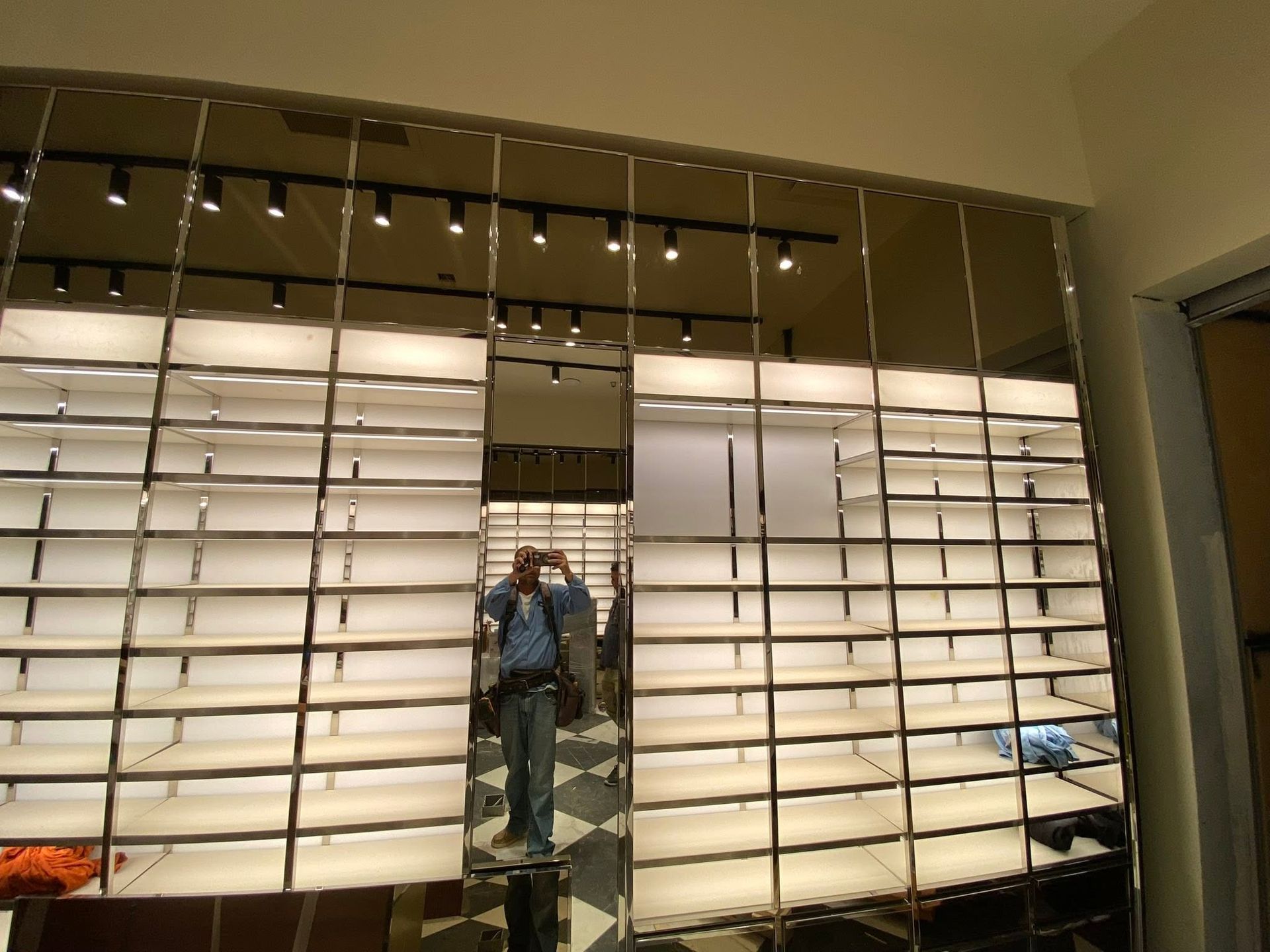 Person standing in front of a large wall of white shutters in a modern interior