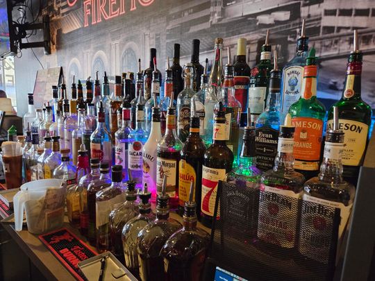 Bar with many liquor bottles on display, brightly lit.