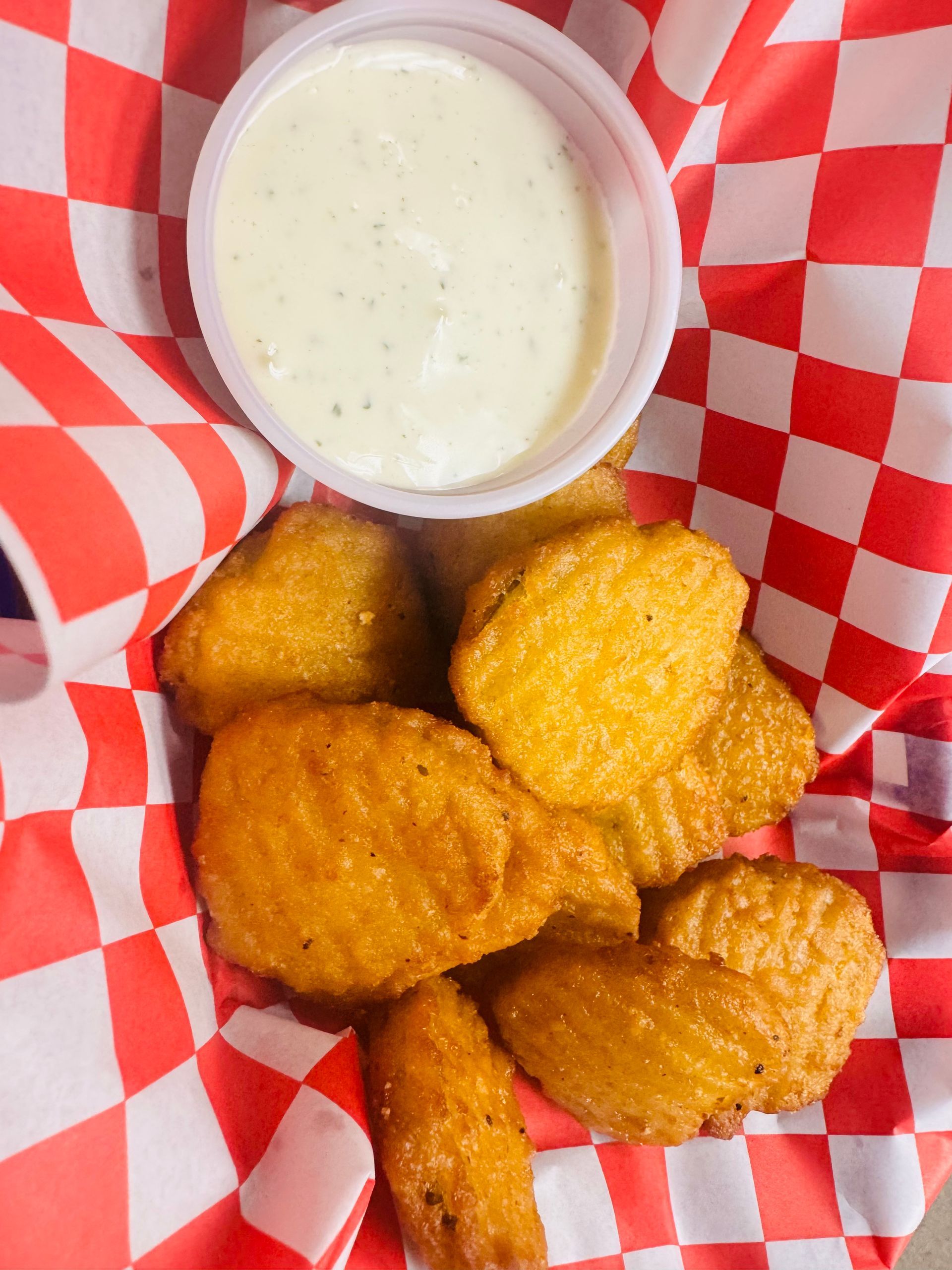 Fried pickles in a basket served with a side of ranch.