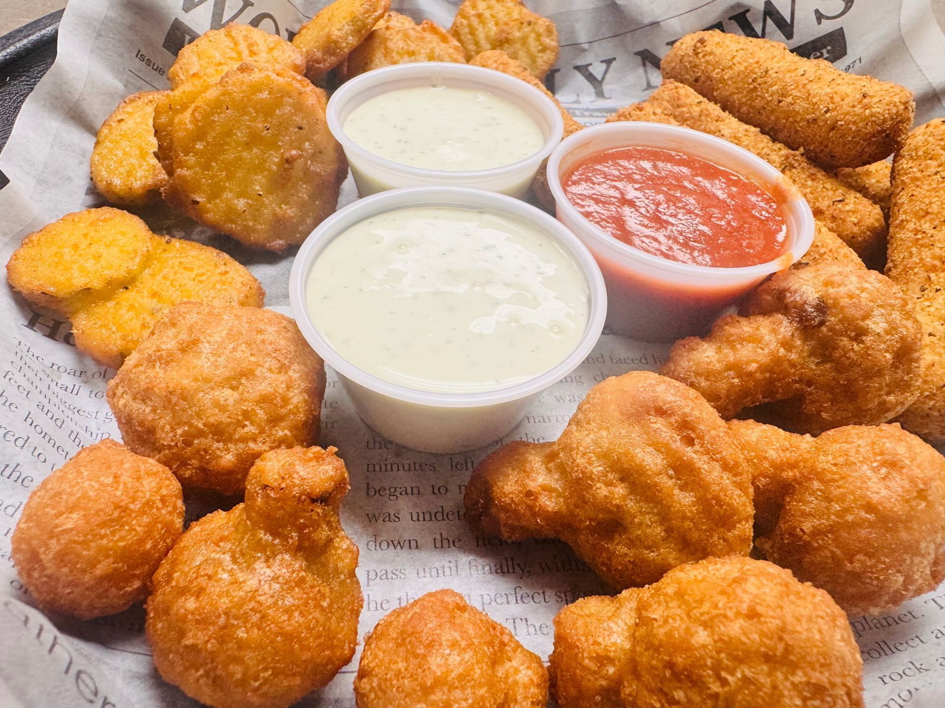 Close up images or three fried appetizers in the 3 Alarm Platter. Fried pickles, fried cauliflower and mozzarella sticks with a side or ranch and marinara sauce in the middle of the platter.