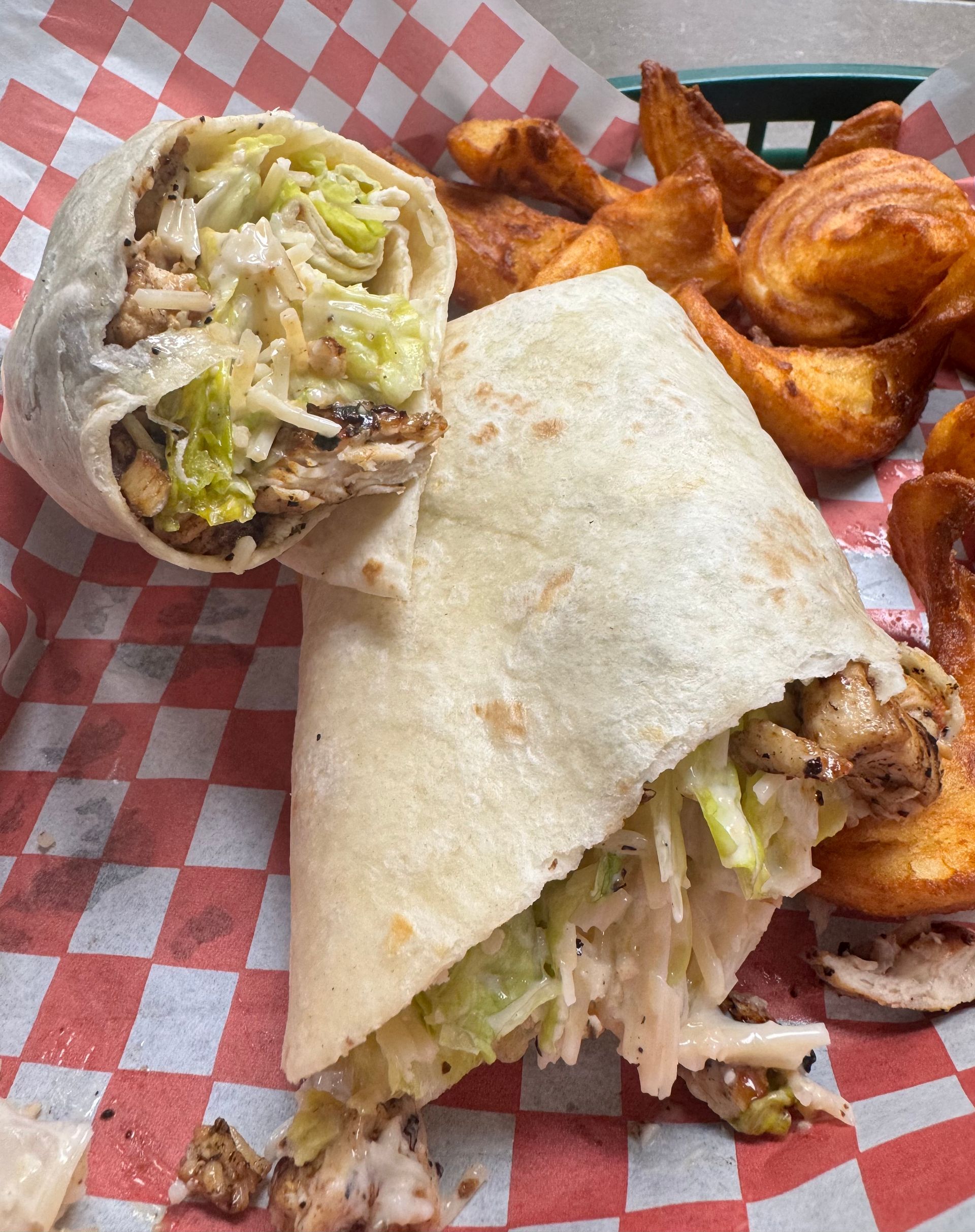 Beer battered fried next to a grilled chicken Caesar wrap cut in half to show the parmesan cheese and lettuce and grilled chicken