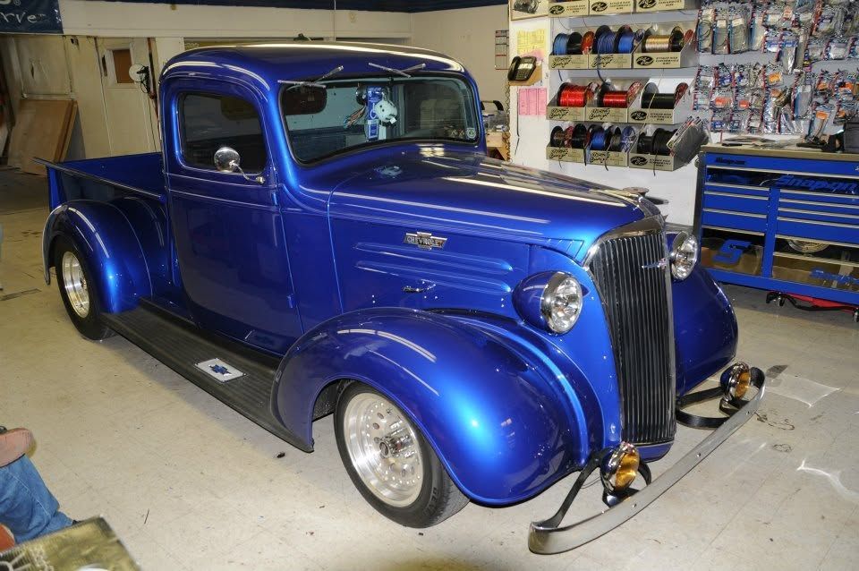 Blue vintage hot rod pickup truck in a garage, with polished chrome details and custom wheels