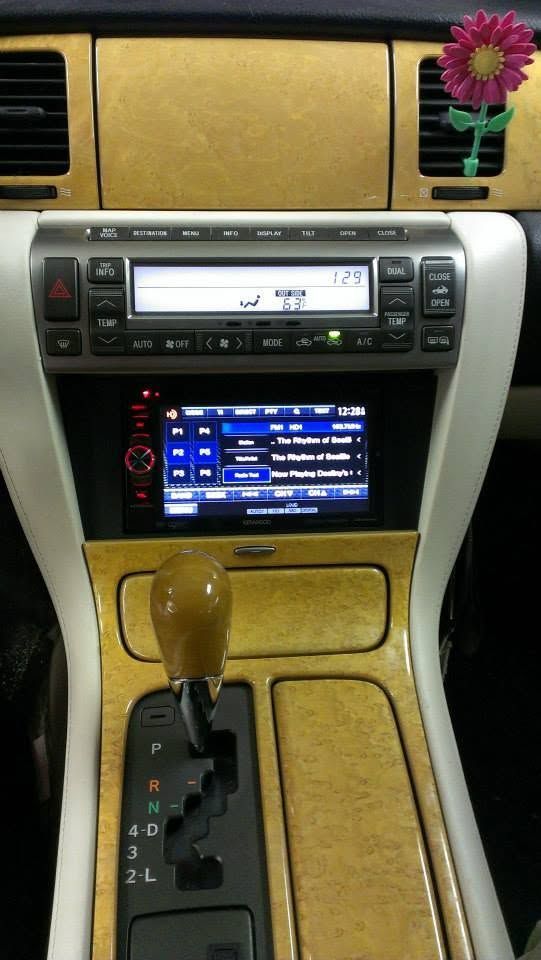 Car dashboard center console with radio and climate controls, tan trim, and flower decoration