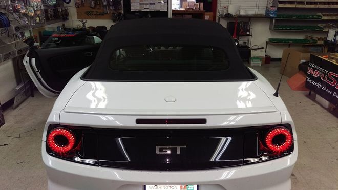 Rear view of a white sports car with black roof and red taillights in a showroom