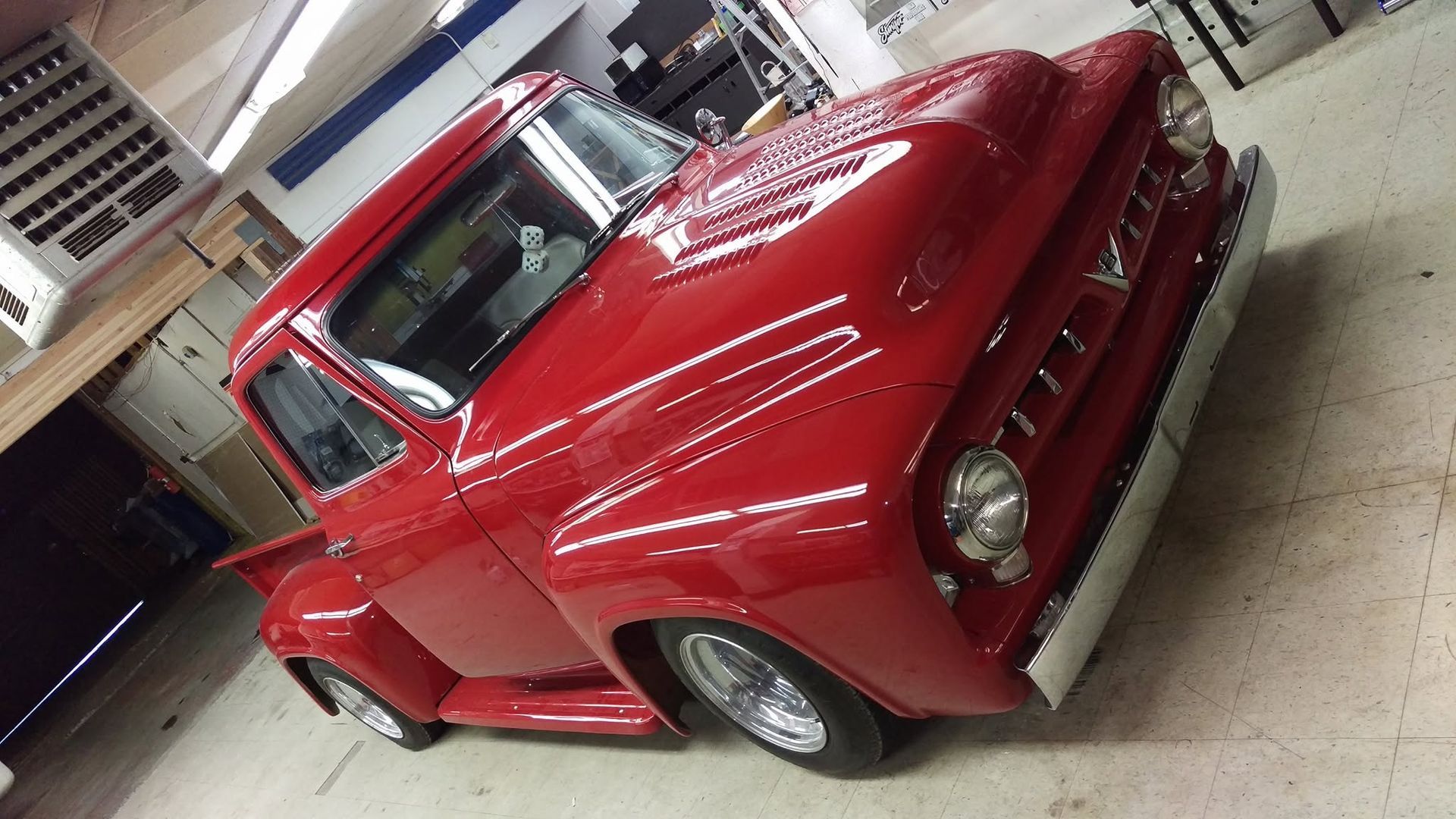 Red classic pickup truck parked indoors in a garage or workshop