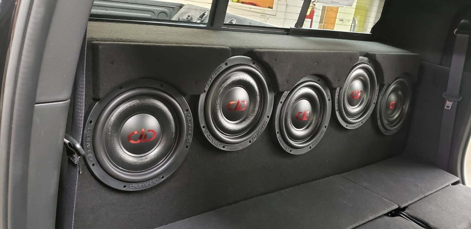 Four black subwoofers mounted in the rear of a vehicle