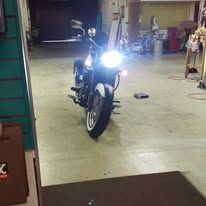 Motorcycle with bright headlight parked indoors in a garage or workshop