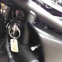 Close-up of motorcycle ignition with key inserted and a hanging key tag