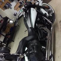 Black motorcycle with silver accents parked indoors on a garage floor.