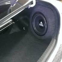 Car trunk with a large black subwoofer speaker installed on the right side.