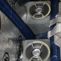 Two round speakers mounted in a gray-and-blue car audio enclosure