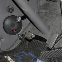 Close-up of a car speaker and seatbelt buckle on a carbon-fiber patterned seat area