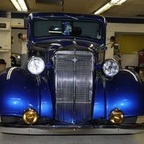 Front view of a blue vintage car in a garage, with chrome grille and round headlights