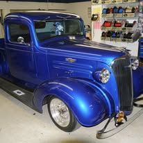 Blue vintage coupe parked in a garage, shown from the front-left side