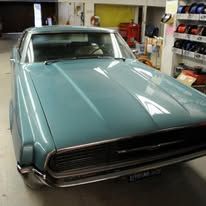Classic teal car parked inside a garage, front view