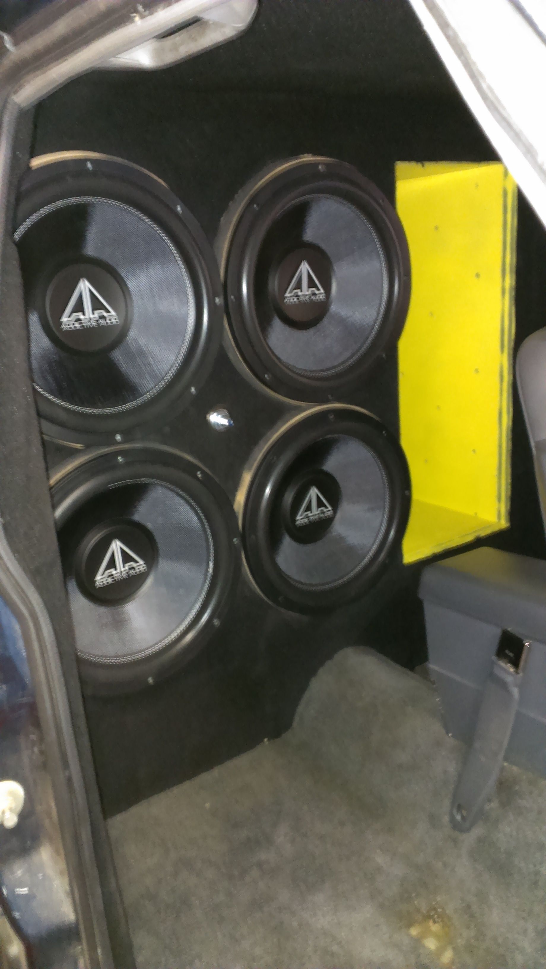 Six black speaker drivers arranged on a yellow board with blue padding around it