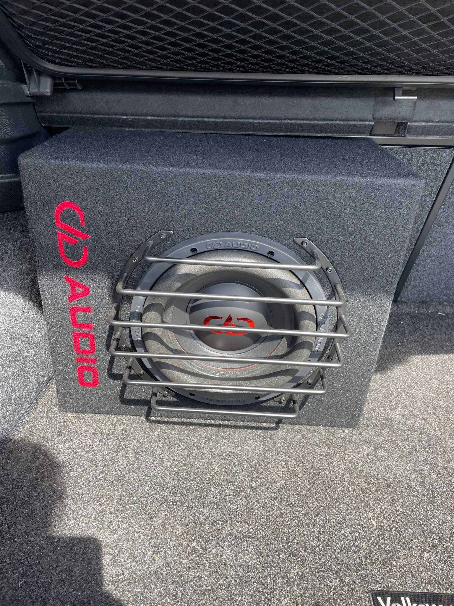 Car subwoofer in a black enclosure with a metal grille and red “Audi” lettering